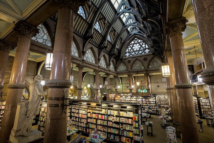 Grandiose library interior with towering columns, arched ceilings, and shelves filled with books in a magical setting.